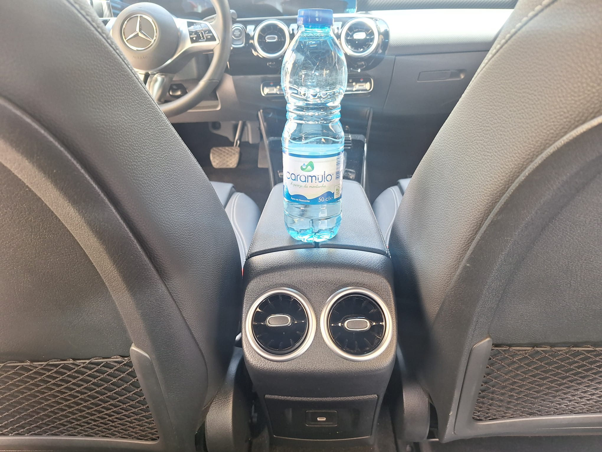 Rear passenger view of the car interior with bottled water and air vents